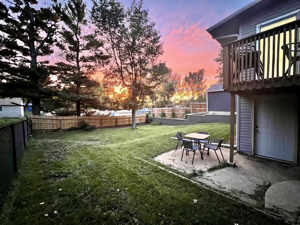 Multilevel deck, patio, & lawn. Equipped with tables, chairs, and propane grill.