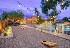 The backyard area has lighting around the landscape and overhead lights for game