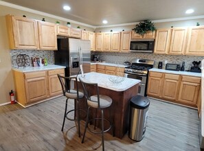 Full kitchen with stainless steel side-by-side refrigerator, double oven & more