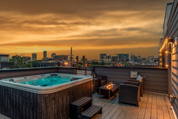 Private outdoor rooftop deck with stunning city views featuring a relaxing hot tub, firepit with outdoor furnishings, BBQ grill, and outdoor dining.
