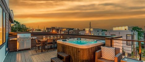 Private outdoor rooftop deck with stunning city views featuring a relaxing hot tub, firepit with outdoor furnishings, BBQ grill, and outdoor dining.