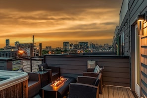 Private outdoor rooftop deck with stunning city views featuring a relaxing hot tub, firepit with outdoor furnishings, BBQ grill, and outdoor dining.