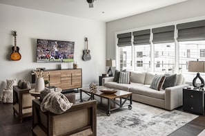 Bright and open living area with flat screen TV, and designer furnishings.