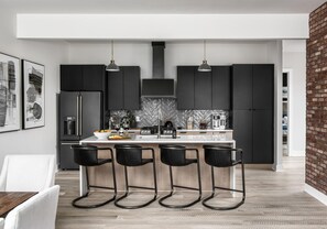 Sleek and modern kitchen with all black cabinetry and appliances. Island with bar seating.