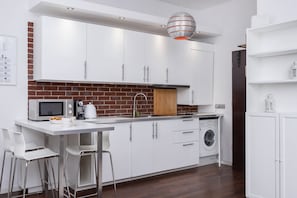 Modern kitchen fully equipped with white cabinets and wooden accents.
