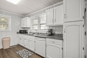 fully stocked kitchen with dishwasher, microwave, coffee maker, full size fridge