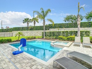 Heated spa and pool view with sunbathing chairs and basketball ring