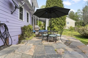 Back patio with grill, table and lit umbrella