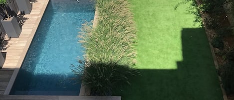 Vue sur l'extérieur avec transat, piscine, parasol, table et chaises de jardin 