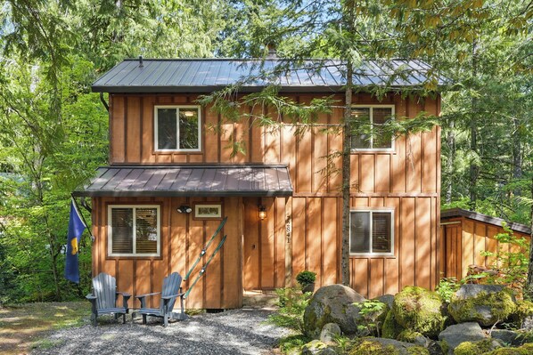 Charming cabin exterior nestled in lush forest scenery.