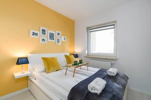 Bright bedroom with a comfortable double bed and artistic wall frames.
