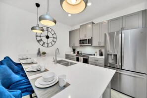 Polished kitchen of the townhouse in Kissimmee Florida - Well-lit workspace with strategically placed task lighting - Integrated appliances for a seamless and stylish appearance - Breakfast bar and high chairs