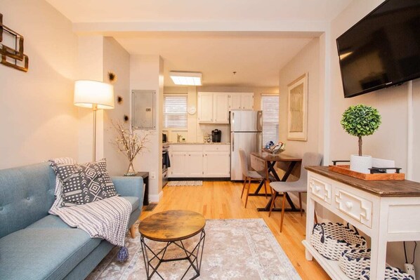 Living Room and Entrance, TV mounted to wall for easy viewing and to keep out of the way. Kitchen can be seen in the background

