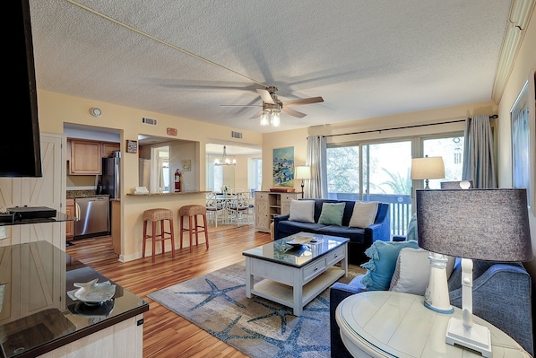 Living Room has a 65" Samsung flat panel Smart TV, new Sofa, new Love Seat Wine Bar cabinet. two end tables and a large card table in front of the Sofa.