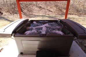 Private covered hot tub holds 6 people while they enjoy views of the woods.