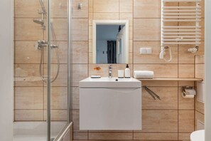 A stylish bathroom with wooden accents, a walk-in shower, and bright lighting.
