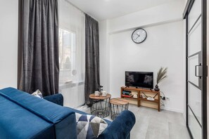A comfortable seating area featuring a blue couch, a rug, and a flat-screen TV.
