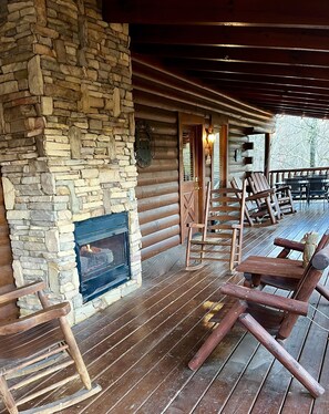 Porch housing main entrance with ample outdoor seating and gas log fireplace. 