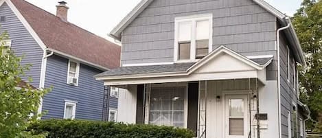 Front of house. Includes small patio with two chairs under front window.