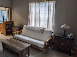 Living room with fold-out futon. Coffee table top lifts for storage and working.