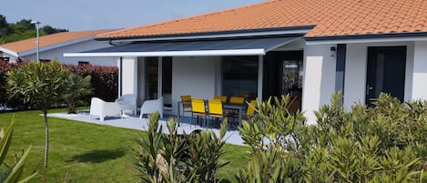 Terrasse façade  sud-est équipée d'un store électrique. Le jardin est clôturé.
