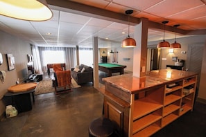 Panaromic photo of entry floor game room with pool table, foosball table, lounge furniture and more!