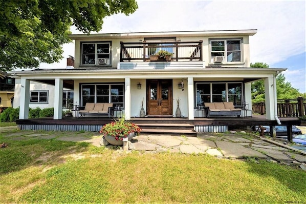 Front of home showcasing upstairs balcony and main floor wrap around porch