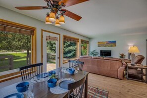 Bright and sunny dining and living area with large windows that display park-like back yard.