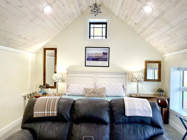 King bed with couch that has 2 recliners comfortably in front of the tv. 