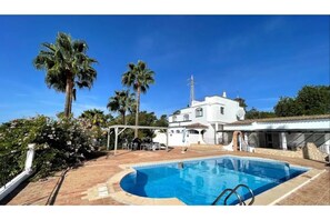 Large pool area with chairs and shade areas overlooking the countryside. 