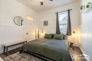 The king sized bedroom - Emmeline's Chambers features ship lap walls, a large window, and cozy accents. 