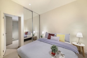 A master bedroom with a queen sized bed & plush pillows.