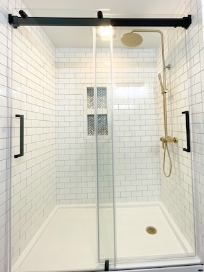 Subway tile shower, gold fixtures.