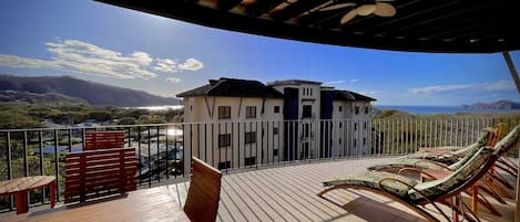 Large, covered balcony with dining table and chaise lounges.