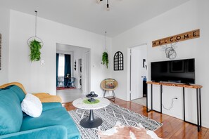 Bright and open living room/kitchen layout. The living room has a 40" smart tv for entertainment and playing music.