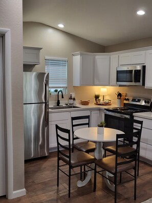 Kitchen with table, fridge, stove, microwave and coffee maker 