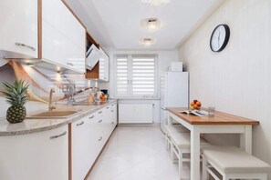 Kitchen with kettle and refrigerator. 