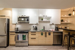 Fully stocked modern kitchen with quartz counters, stainless steel appliances, and all the cookware needed for a gourmet meal