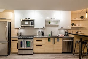 Fully stocked modern kitchen with quartz counters, stainless steel appliances, and all the cookware needed for a gourmet meal