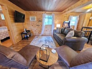 Living room with HD TV,  couch with pull out bed and comfy chairs.