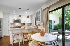 In the dining area, barstools at the kitchen peninsula supplement seating at the dining table for two.
