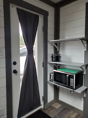 Kitchen entrance, shelving, microwave, toaster, and crockpot.