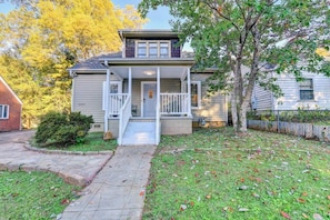 Charming two-story brick house with a spacious front yard, surrounded by lush greenery, creating a picturesque and inviting home.