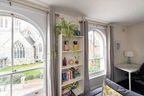 Living Room: Sunlit retreat with charming decor, ample books, and stunning views of historic Portsmouth.