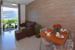 Salle de séjour avec coin repas et canapé-lit, ouverte sur la terrasse panoramique