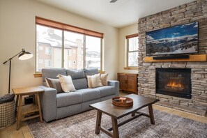 Anther view of living room with large smart TV and gas fireplace.