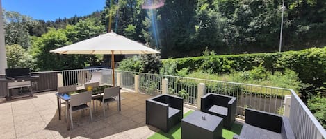 Grande terrasse avec plancha, salon de jardin, table et parasol/