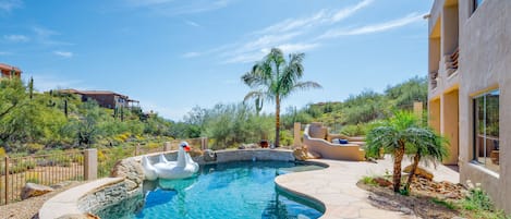 Private oasis with outdoor fireplace, sparkling pool, spa, BBQ grill, corn hole, and multiple lounge areas.