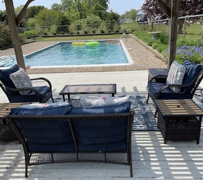 In-ground saltwater pool with spacious deck, sitting area and dining tables.