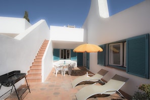 Terrace with sun loungers, parasol, outdoor table and barbecue